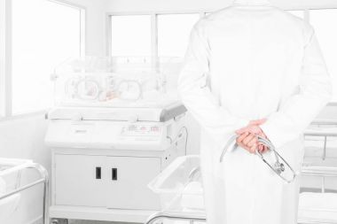 Doktorlar yeni doğan bebek hastane sonrası teslim odasında İnkübatör içinde kaplı bakarak stetoskop ile dikiz görüntü