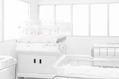 Newborn baby covered inside incubator in hospital post-delivery room clipart