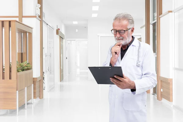 O médico sénior examinou um registo médico no corredor do hospital. — Fotografia de Stock