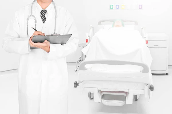 Doctor writing on a folder of diagnosis result in patient room — Stock Photo, Image