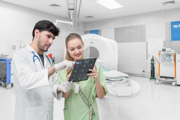 Médico na sala de tomografia examinando um raio-x e discutindo com um paciente — Fotografia de Stock