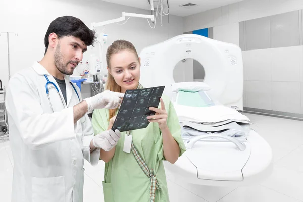 Médico na sala de tomografia examinando um raio-x e discutindo com um paciente — Fotografia de Stock