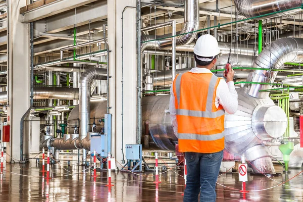 Engineer working in a thermal power plant with talking on the walkie-talkie for controlling work