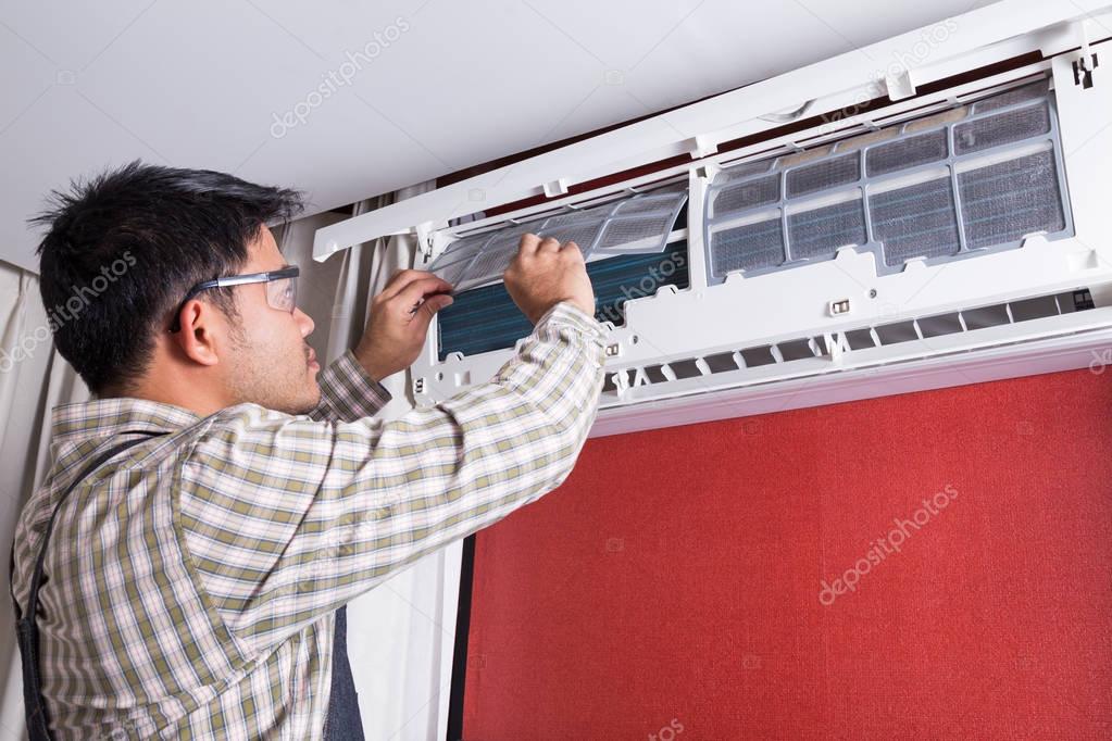Young man electrician cleaning air conditioning in a client hous