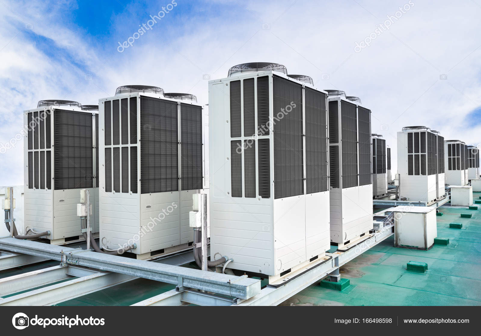 A row of air conditioning units on rooftop with blue sky Stock Photo by