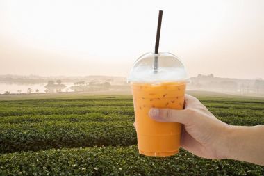 Buz süt çay çay alan arka plan üzerinde tutan el