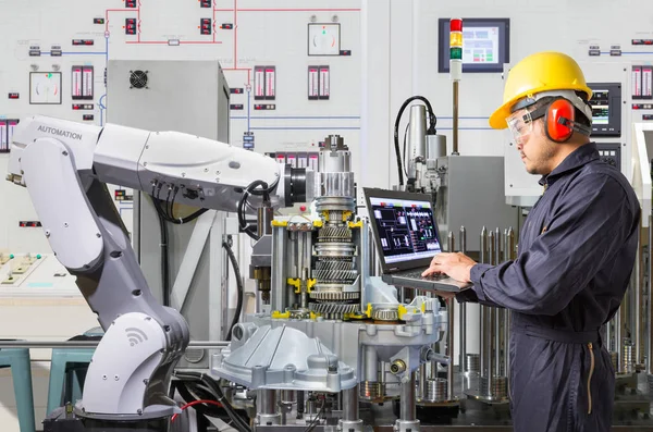 Ingeniero que utiliza el ordenador portátil para el mantenimiento automático de la máquina herramienta robótica en la industria automotriz — Foto de Stock