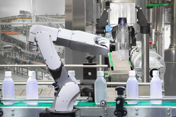 Роботизированная рука, удерживающая бутылки с водой на линии по производству напитков на заводе, концепция Индустрии 4.0 — стоковое фото