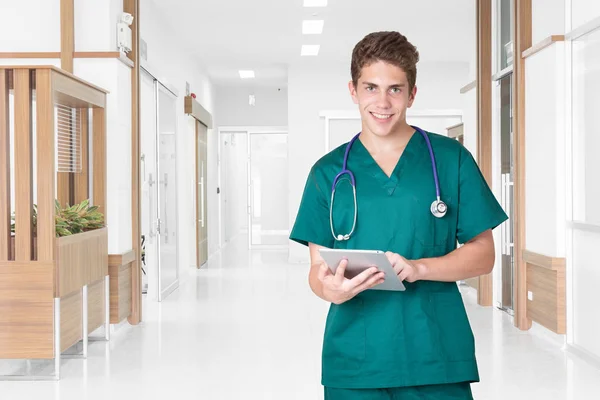 Jovem médico sorrindo usando tablet no corredor do hospital — Fotografia de Stock