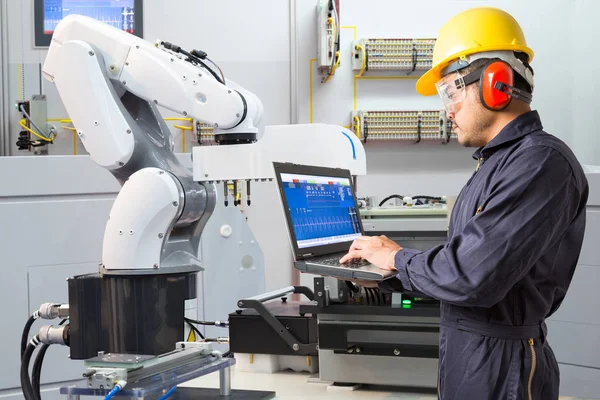 Ingegnere che utilizza il computer portatile per la manutenzione automatica della macchina utensile manuale robotica in fabbrica intelligente, concetto di Industria 4.0 — Foto Stock