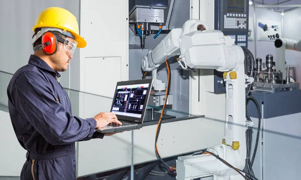 Ingeniero que utiliza el ordenador portátil para el mantenimiento automático de la máquina herramienta robótica en la industria automotriz — Foto de Stock