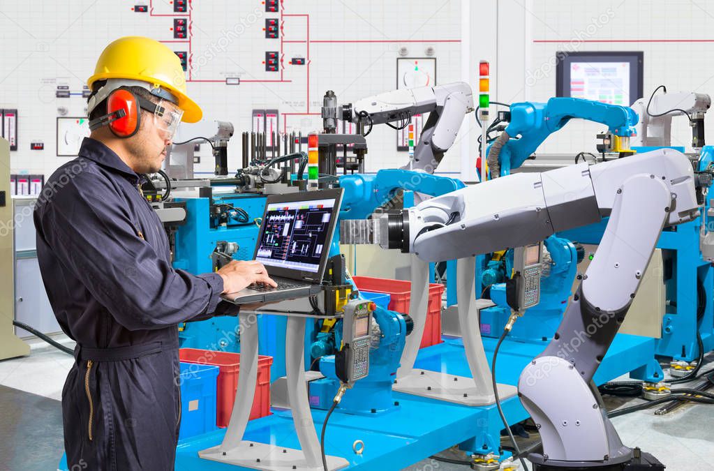 Engineer using laptop computer for maintenance automatic robotic hand machine tool at industrial manufacture factory
