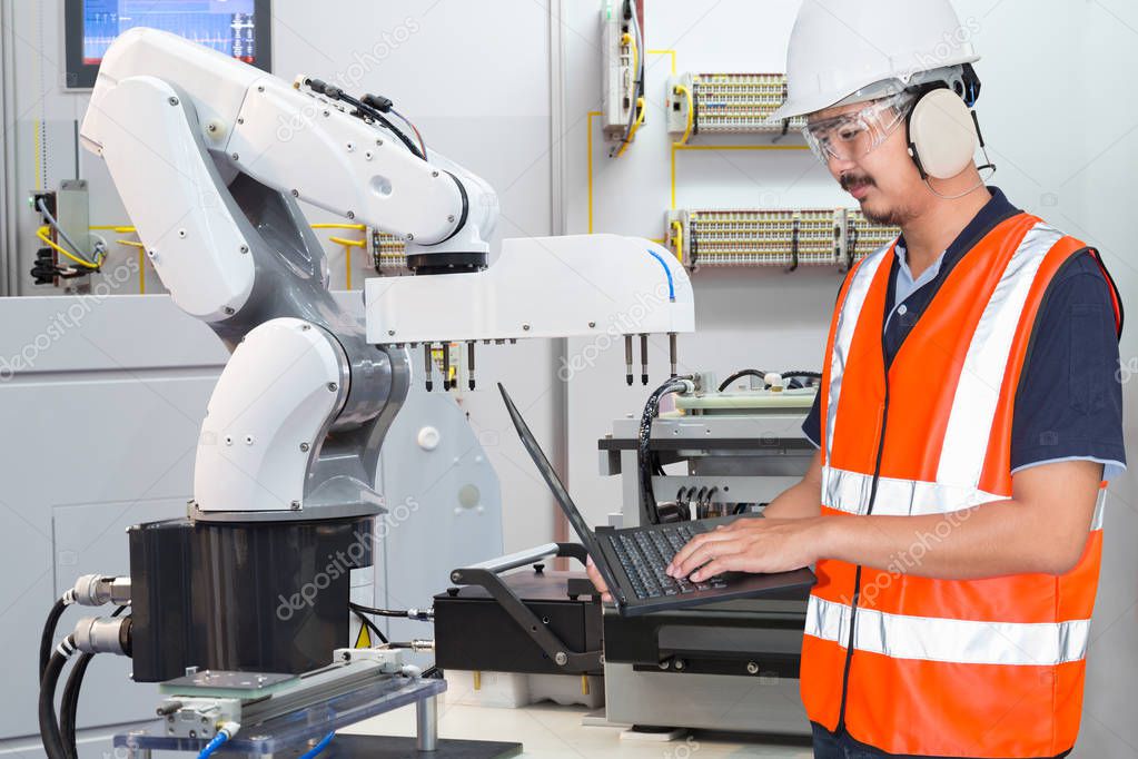 Engineer using laptop computer for maintenance automatic robotic hand machine tool in electronic smart factory, Industry 4.0 concept