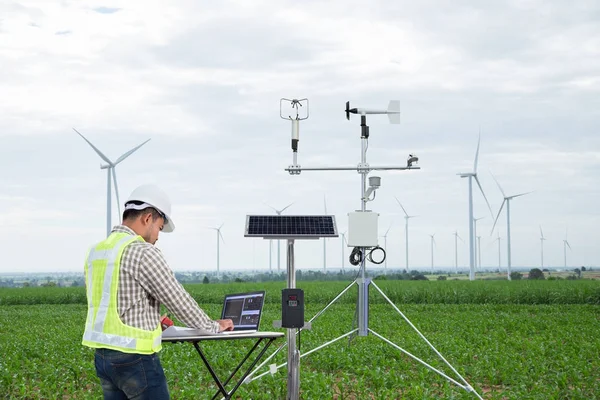 Ingeniero que utiliza la computadora de la tableta recopila datos con el instrumento meteorológico para medir la velocidad del viento, la temperatura y la humedad y el sistema de células solares en el fondo del campo de maíz, concepto de tecnología agrícola inteligente —  Fotos de Stock