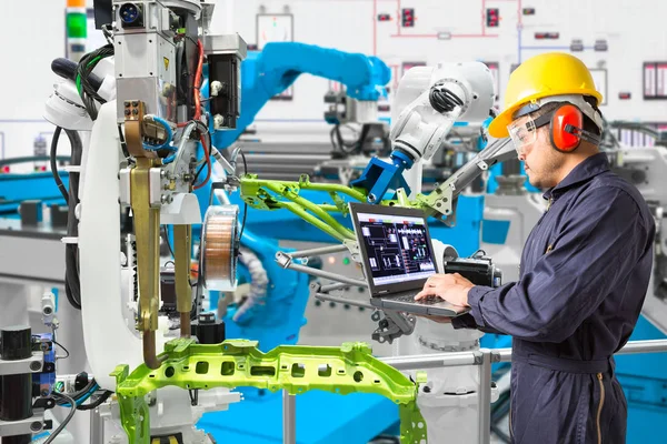 Engenheiro usando computador portátil de manutenção de soldagem robótica automática com peça de robô na indústria automotiva, conceito de fábrica inteligente — Fotografia de Stock