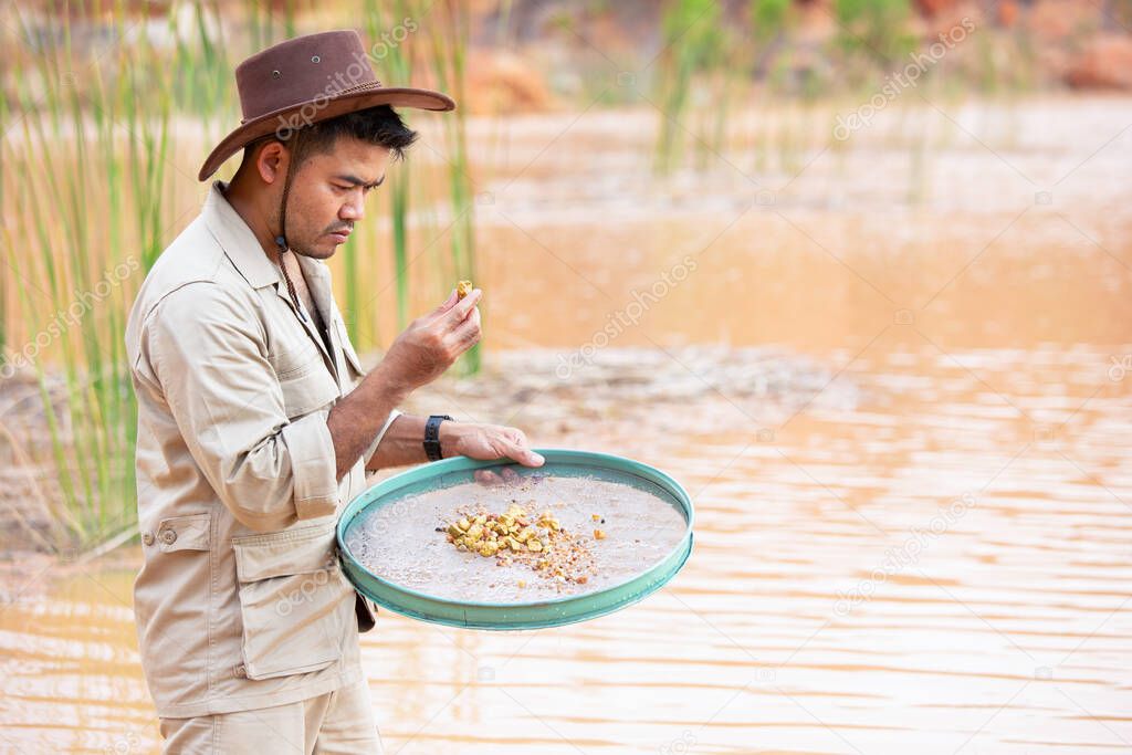 Gold prospector holds up specimen of gold nugget