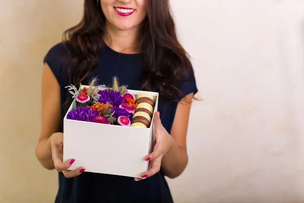 Žena držící rámeček s květinami a makronky soubory cookie — Stock fotografie