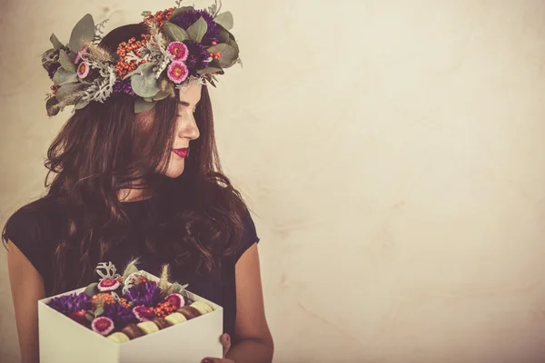 Kvinna som håller en låda med blommor och macaroon cookies — Stockfoto