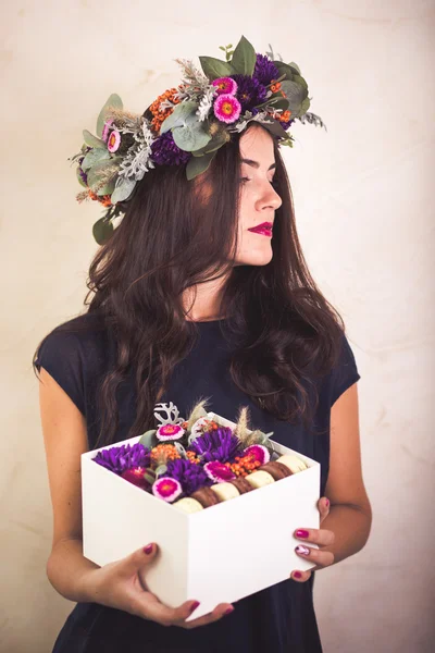 Nő a gazdaság egy doboz virágok és macaroon cookie-k — Stock Fotó