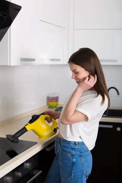 Nainen puhdistaa keittiö höyrypuhdistimella — kuvapankkivalokuva