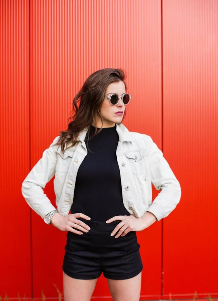 Stylische Frau steht an roter Wand — Stockfoto