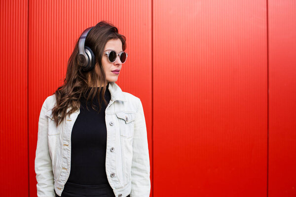 Stylish woman standing near red wall