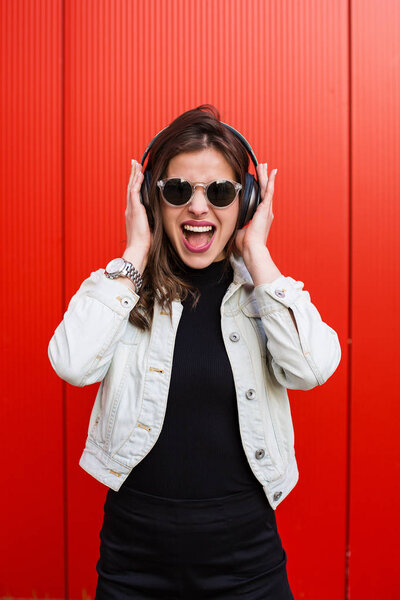 Stylish woman standing near red wall