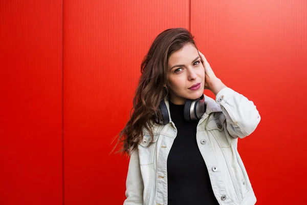 Snygg kvinna som står nära röda väggen — Stockfoto