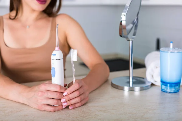 Woman with a toothbrush and an oral irrigator — Stock Photo, Image