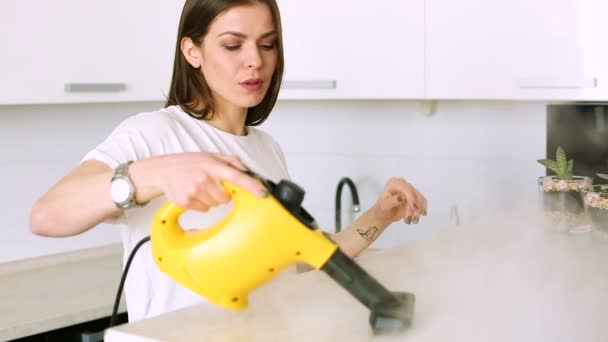Vrouw schoonmaak van de keuken met een stoom reiniger — Stockvideo