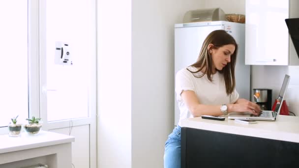 Vrouw in haar keuken met een laptop — Stockvideo