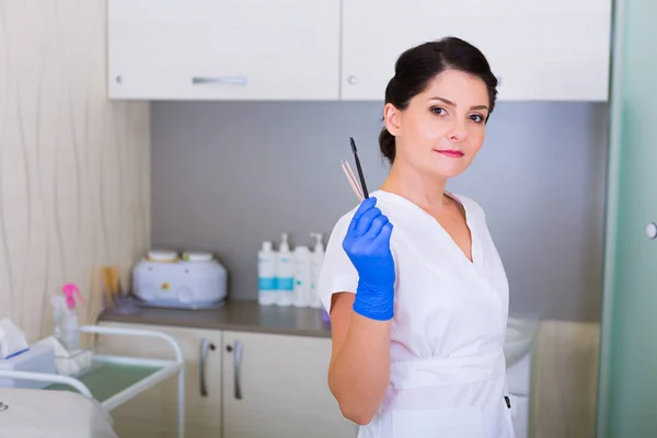 Woman cosmetologist with a brush and a cosmetic tweezers — Stock Photo, Image