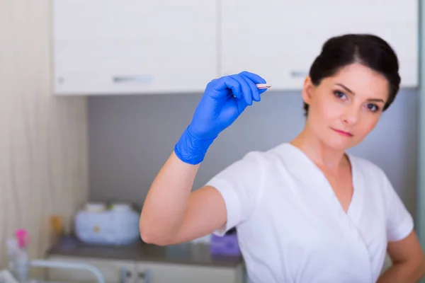 Mujer cosmetóloga con un cepillo y unas pinzas cosméticas — Foto de Stock