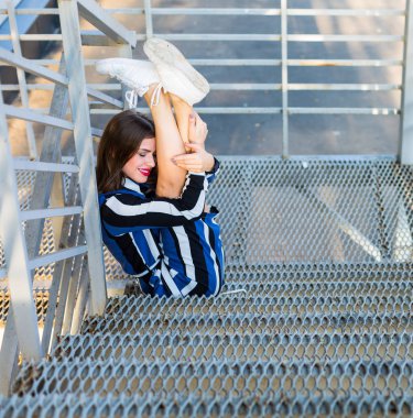 Metal merdivenlerde oturan kadın