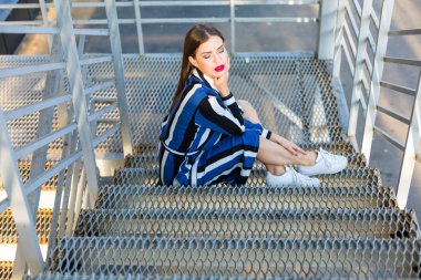 Metal merdivenlerde oturan kadın