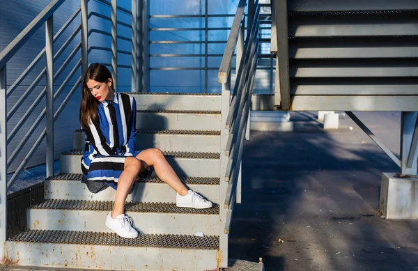 Metal merdivenlerde oturan kadın