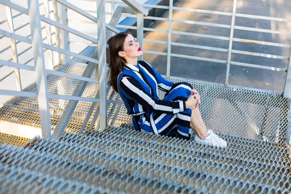 Metal merdivenlerde oturan kadın