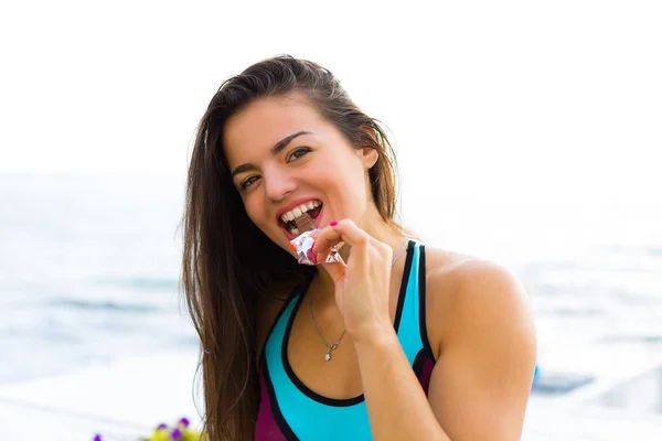 Sporty woman eating chocolate — Stock Photo, Image