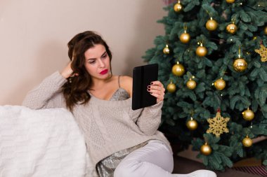 Kadın e-kitap Noel ağacı yakınındaki okuma