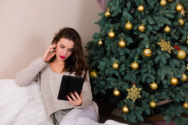 크리스마스 트리 근처 전자-책을 읽는 여자 — 스톡 사진