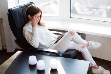 Kadın e-kitap pencerenin yanındaki okuma