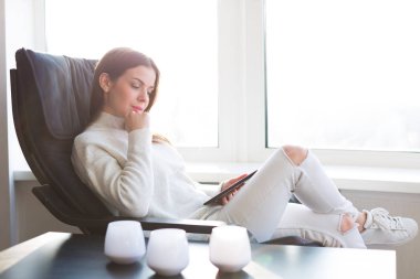 Kadın e-kitap pencerenin yanındaki okuma