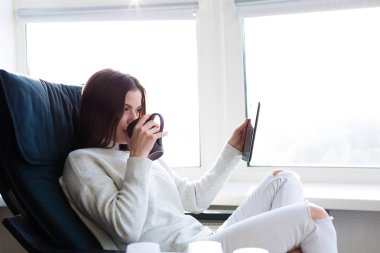 Bir e-kitap ile cam kenarında oturan kadın