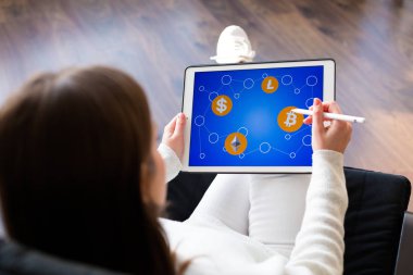 Bir tablet cryptocurrency logoları ile tutan kadın