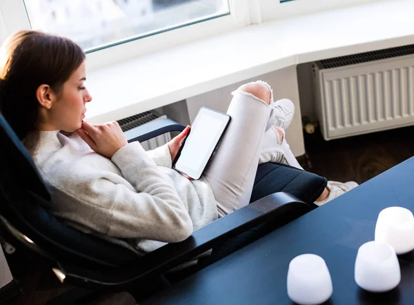 Bir e-kitap ile cam kenarında oturan kadın