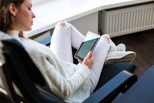 Mujer sentada junto a la ventana con un libro electrónico — Foto de Stock