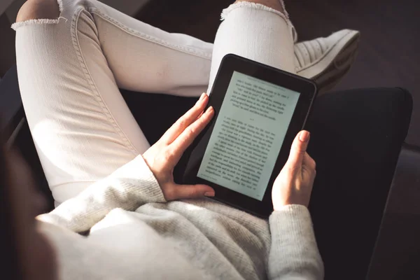 Mujer sentada junto a la ventana con un libro electrónico — Foto de Stock