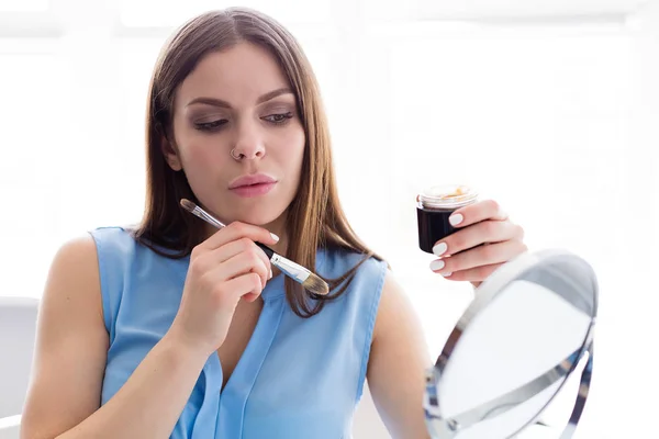 Woman applying a gold mask on her face — Stock Photo, Image