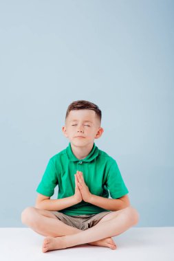 Küçük çocuk yoga yapıyor, mavi arka planda izole edilmiş, fotokopi odası, stüdyo.
