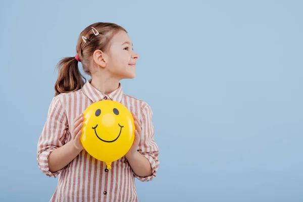 Criança, menina com balão amarelo com sorriso. Olha para o lado. , — Fotografia de Stock